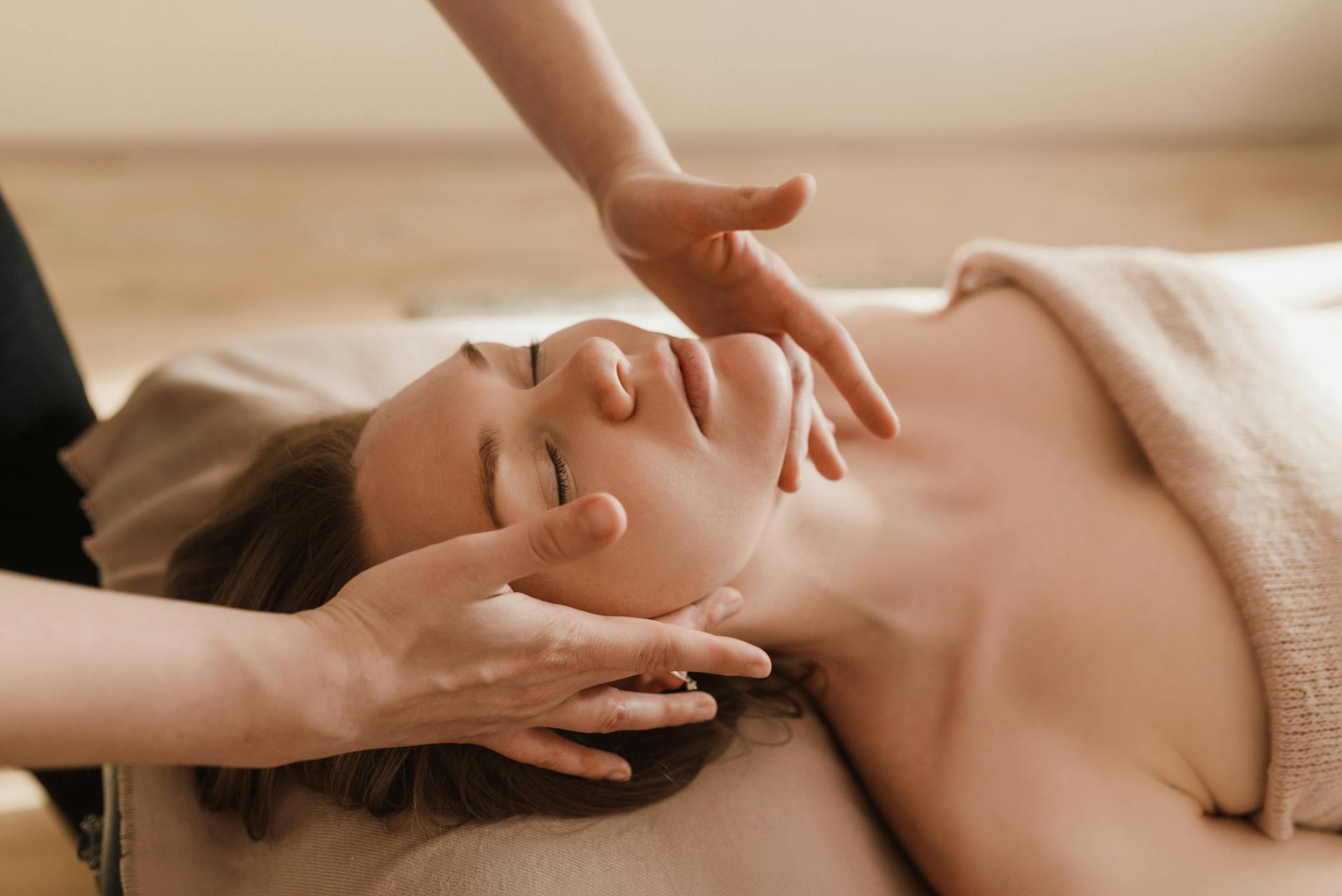 a relaxed woman receives a facial massage