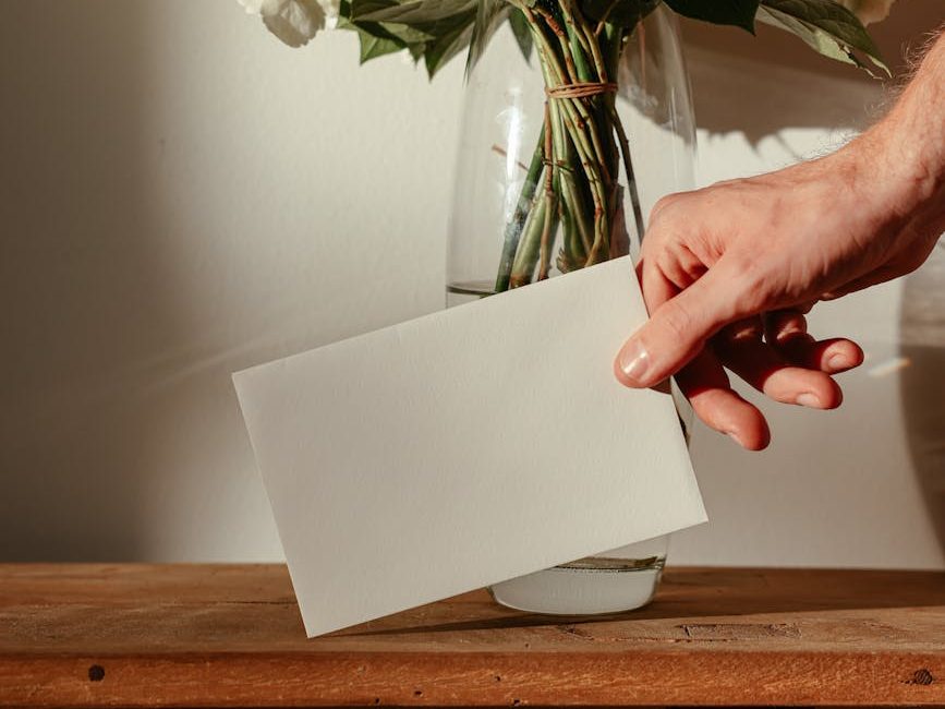 A gift card envelope is placed next to a vase of flowers.